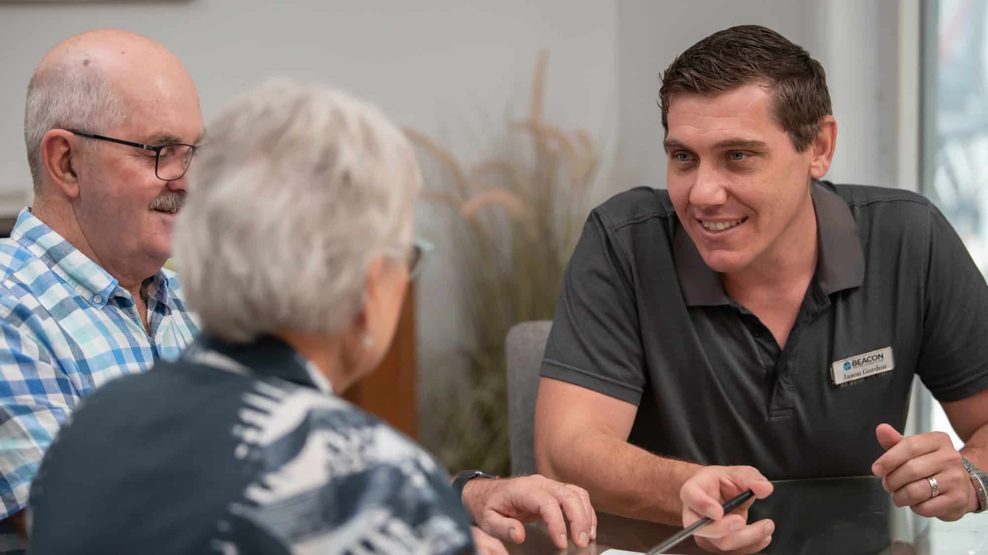 Jason Gordon of Beacon Aged Care & Retirement Advisers with a senior couple during a home visit consultation